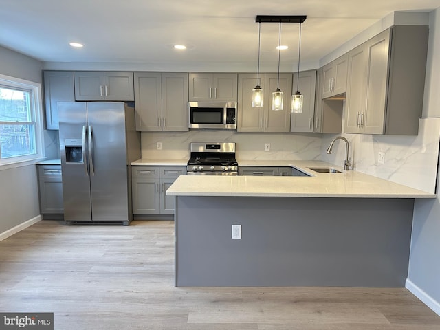 kitchen with gray cabinets, appliances with stainless steel finishes, sink, and decorative light fixtures