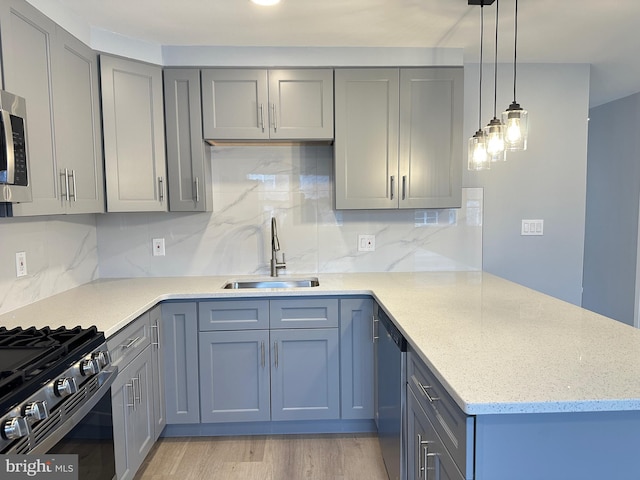 kitchen featuring sink, gas range, decorative light fixtures, stainless steel dishwasher, and light stone countertops