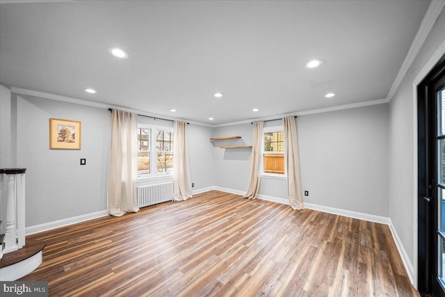 unfurnished living room featuring crown molding, radiator, and hardwood / wood-style floors