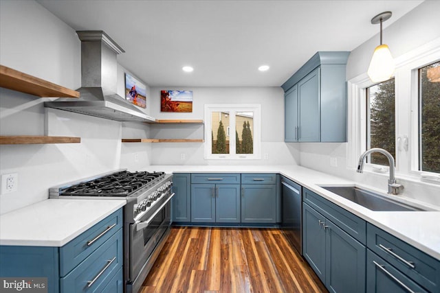 kitchen with sink, hanging light fixtures, stainless steel appliances, dark hardwood / wood-style floors, and wall chimney exhaust hood