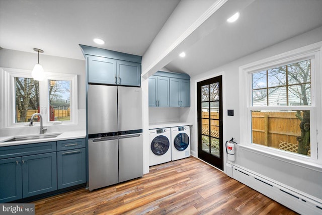 washroom with washer and dryer, sink, hardwood / wood-style floors, and baseboard heating