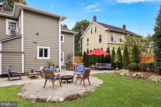 rear view of house featuring an outdoor living space with a fire pit, a patio area, and a lawn