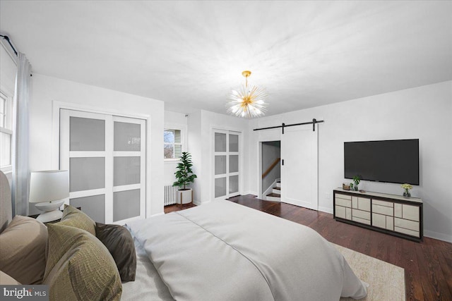 bedroom with radiator, an inviting chandelier, multiple windows, dark hardwood / wood-style floors, and a barn door