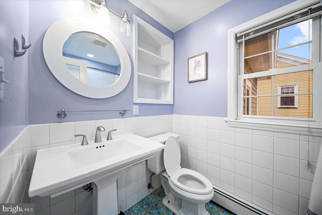 bathroom with baseboard heating, toilet, sink, and tile walls