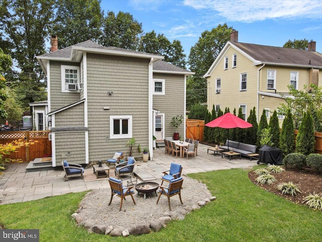 rear view of property with a lawn, an outdoor living space with a fire pit, and a patio area