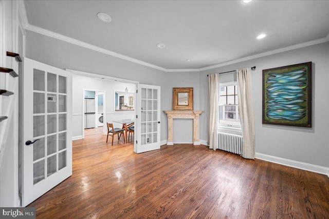 interior space featuring stacked washing maching and dryer, radiator, hardwood / wood-style flooring, ornamental molding, and french doors