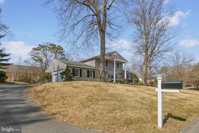 view of front of home with an attached garage, stone siding, and a front yard