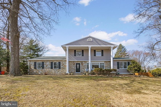 neoclassical / greek revival house with a front yard and stone siding