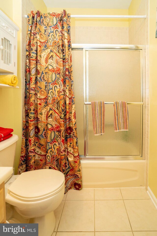 bathroom with tile patterned flooring, tiled shower / bath combo, and toilet