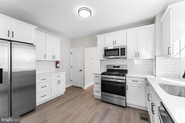 kitchen with white cabinetry, sink, stainless steel appliances, and light wood-type flooring