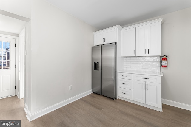 kitchen featuring decorative backsplash, stainless steel fridge with ice dispenser, light hardwood / wood-style flooring, and white cabinets