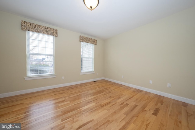 empty room with visible vents, light wood-style flooring, and baseboards