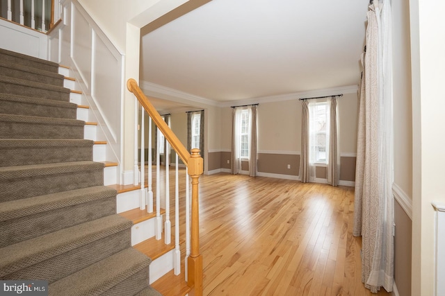 entrance foyer featuring ornamental molding, wood-type flooring, baseboards, and stairs