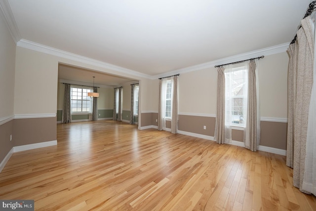 unfurnished living room featuring light wood-style flooring, ornamental molding, and baseboards