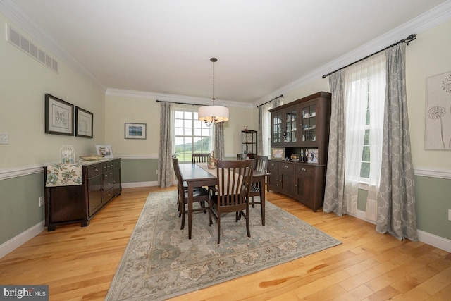 dining area with ornamental molding, visible vents, a notable chandelier, and light wood finished floors