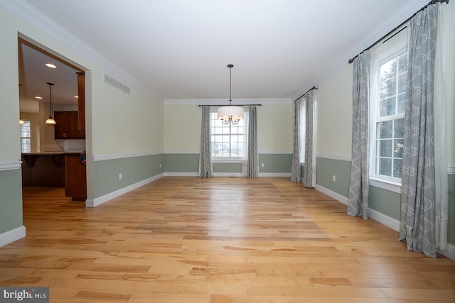 unfurnished dining area with light wood-style flooring, visible vents, a chandelier, and ornamental molding