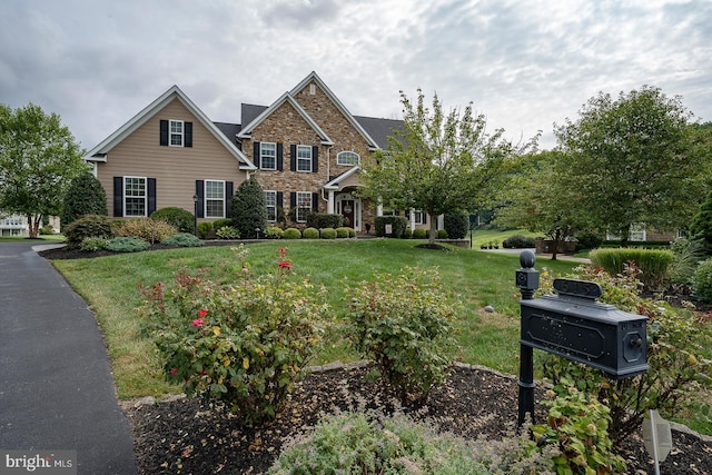 view of front of house featuring stone siding, a front lawn, and brick siding