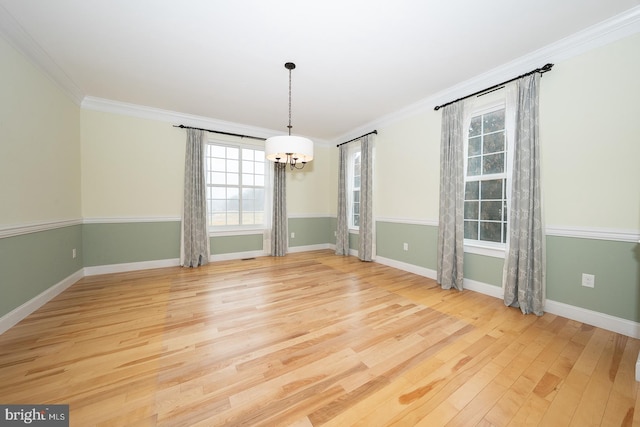 unfurnished dining area with a chandelier, baseboards, crown molding, and light wood finished floors