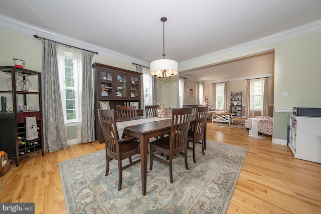 dining area featuring light wood finished floors, an inviting chandelier, a wealth of natural light, and crown molding