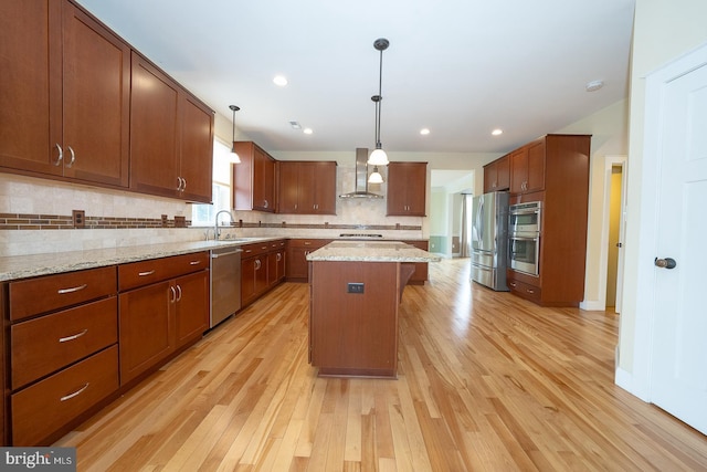 kitchen with wall chimney exhaust hood, a kitchen island, light stone counters, hanging light fixtures, and stainless steel appliances