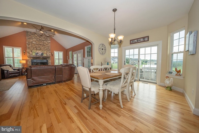 dining room featuring lofted ceiling, plenty of natural light, a fireplace, and light wood-style flooring