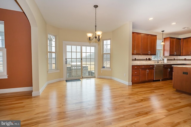 kitchen with light wood-style flooring, open floor plan, hanging light fixtures, dishwasher, and plenty of natural light