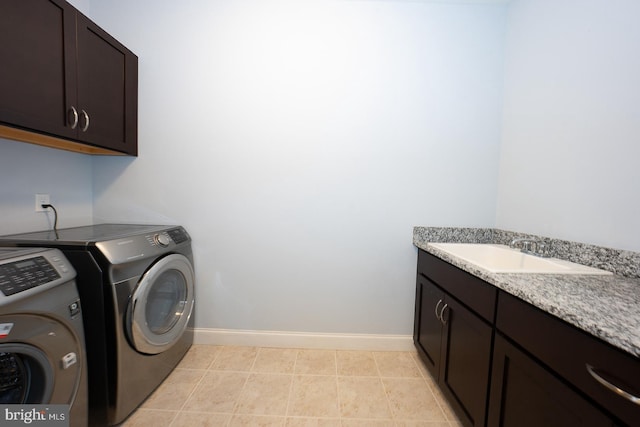 clothes washing area with washer and clothes dryer, light tile patterned floors, cabinet space, a sink, and baseboards