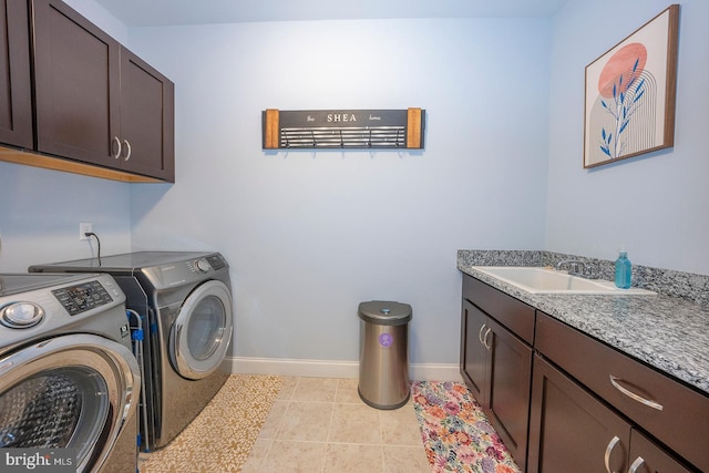 washroom featuring light tile patterned floors, a sink, baseboards, cabinet space, and washing machine and clothes dryer