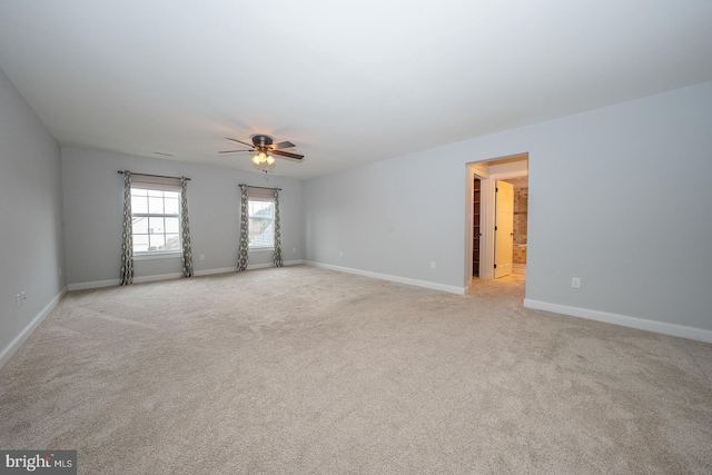 empty room featuring baseboards, a ceiling fan, and light colored carpet