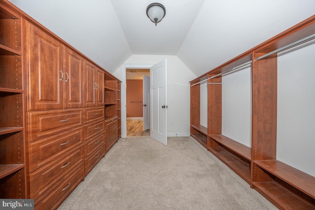 spacious closet with light carpet and vaulted ceiling