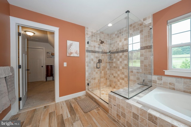 full bathroom featuring a stall shower, baseboards, a garden tub, and wood finished floors