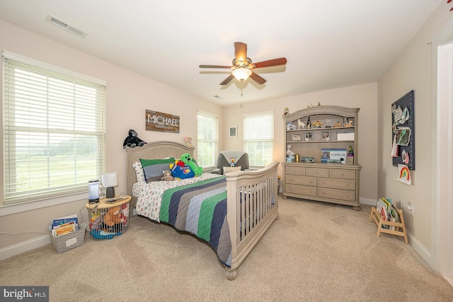 bedroom with a ceiling fan, light colored carpet, visible vents, and baseboards