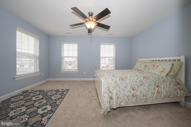 bedroom with light carpet, ceiling fan, visible vents, and baseboards