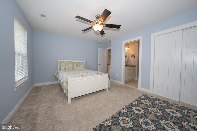 bedroom with visible vents, ensuite bathroom, a ceiling fan, light carpet, and baseboards