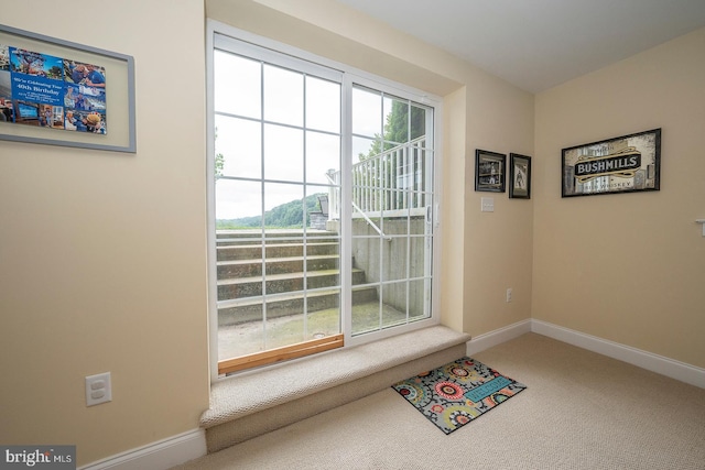 doorway with carpet floors and baseboards