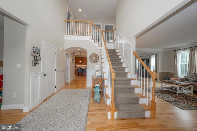 stairs with arched walkways, a high ceiling, and wood finished floors