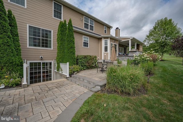 back of house featuring a patio area and a lawn