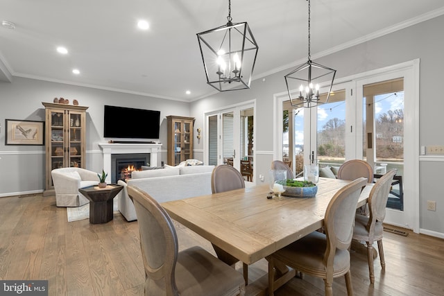 dining area with crown molding, an inviting chandelier, light hardwood / wood-style floors, and french doors