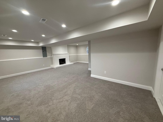 basement with a fireplace and dark carpet