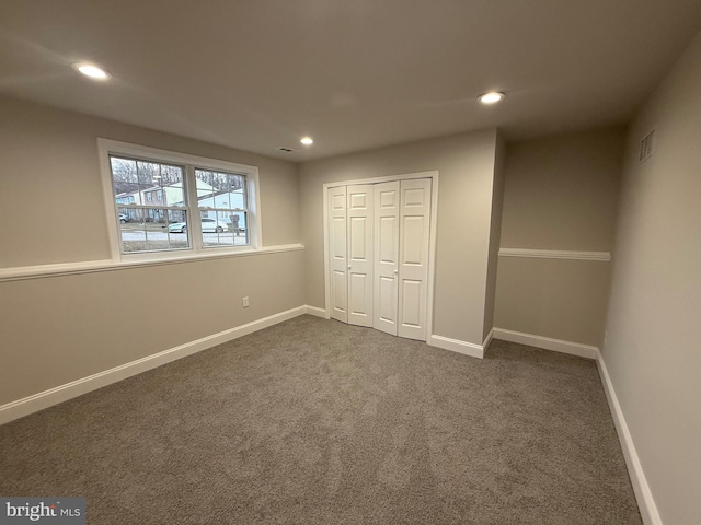 unfurnished bedroom with dark carpet and a closet