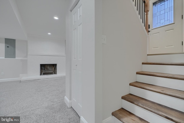 stairway featuring carpet, electric panel, and a brick fireplace