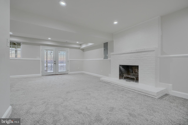 unfurnished living room with a brick fireplace, french doors, and carpet