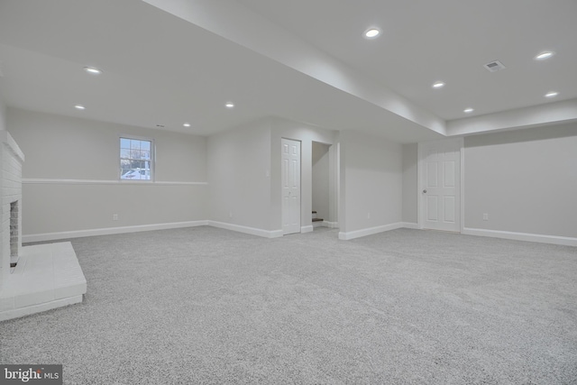 basement featuring a brick fireplace and light carpet