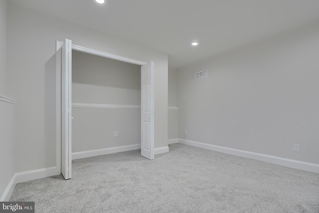 unfurnished bedroom with light colored carpet and a closet