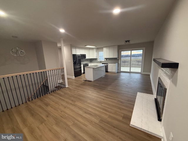 kitchen featuring white cabinetry, a kitchen island, hardwood / wood-style floors, and black appliances