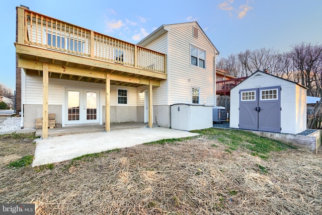 rear view of property with french doors, a patio area, central air condition unit, a deck, and a shed