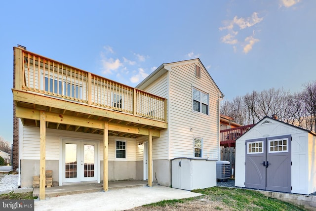 rear view of property featuring french doors, a patio area, cooling unit, a wooden deck, and a shed