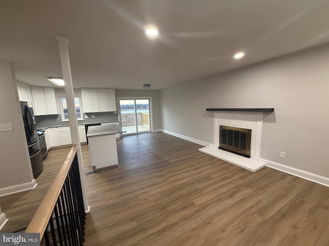 unfurnished living room featuring dark wood-type flooring and a fireplace