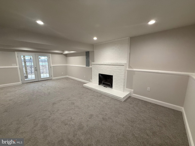 unfurnished living room featuring a fireplace, french doors, and carpet