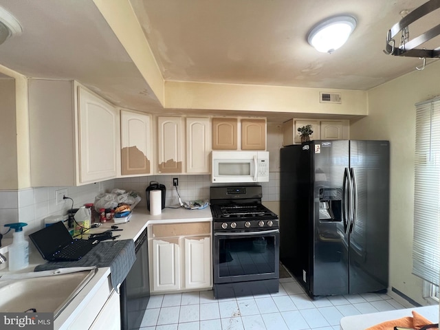 kitchen with tasteful backsplash, sink, light tile patterned floors, and black appliances